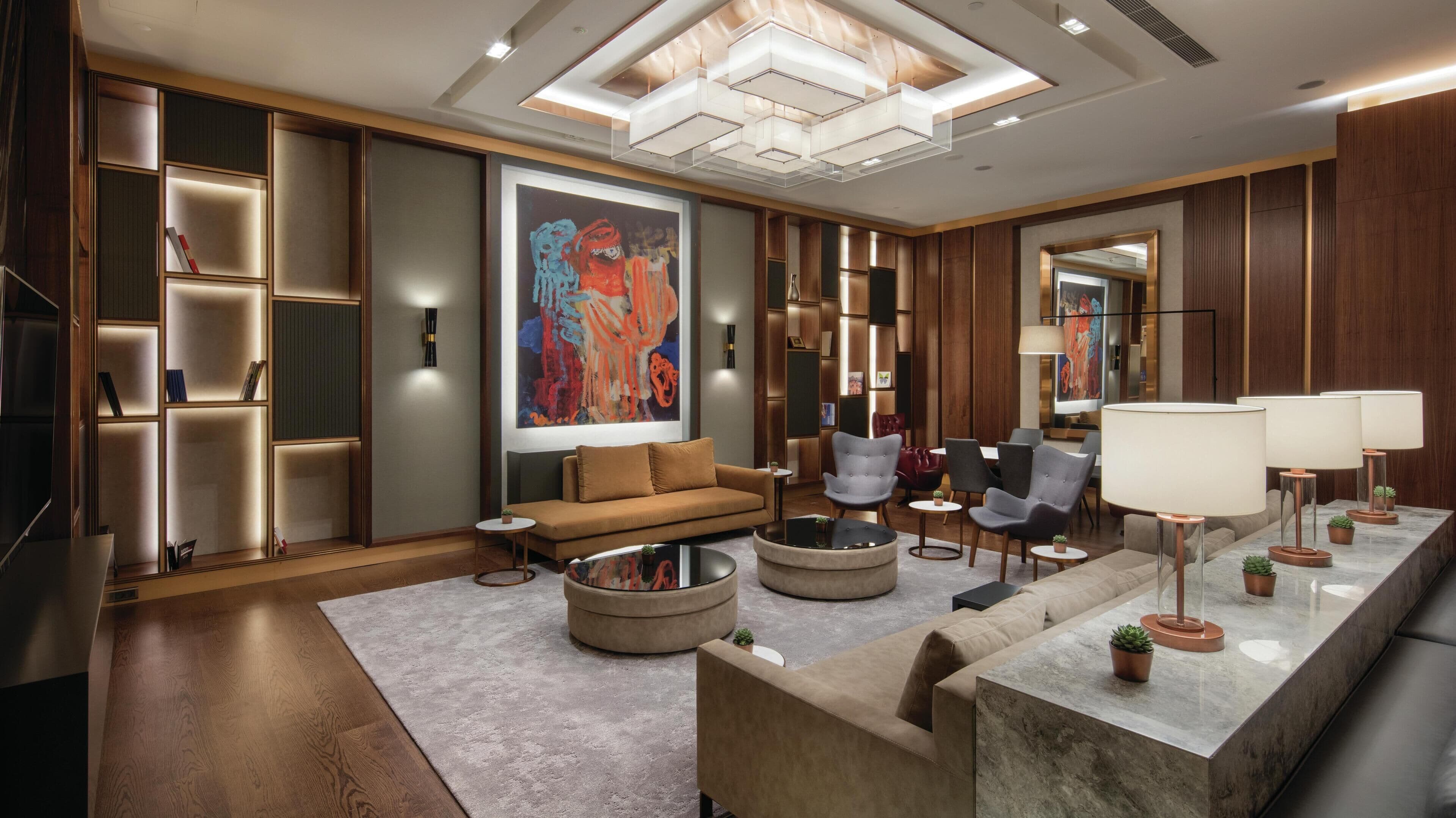 A modern living room with a sofa, armchairs, a coffee table, and a large abstract painting.