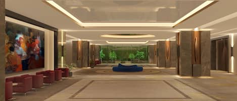 A spacious lobby with a large painting, red seating, a blue sofa, and a view through the glass wall.
