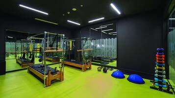 A gym with exercise equipment, a mirrored wall, and a green floor.