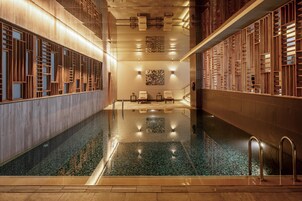 Una piscina interior moderna con paneles de madera y fondo de cristal transparente.