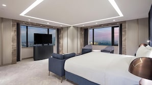 A modern hotel room with a large bed, a flat-screen TV, a seating area, and large windows offering city views. - Hilton Istanbul Maslak (Sariyer)