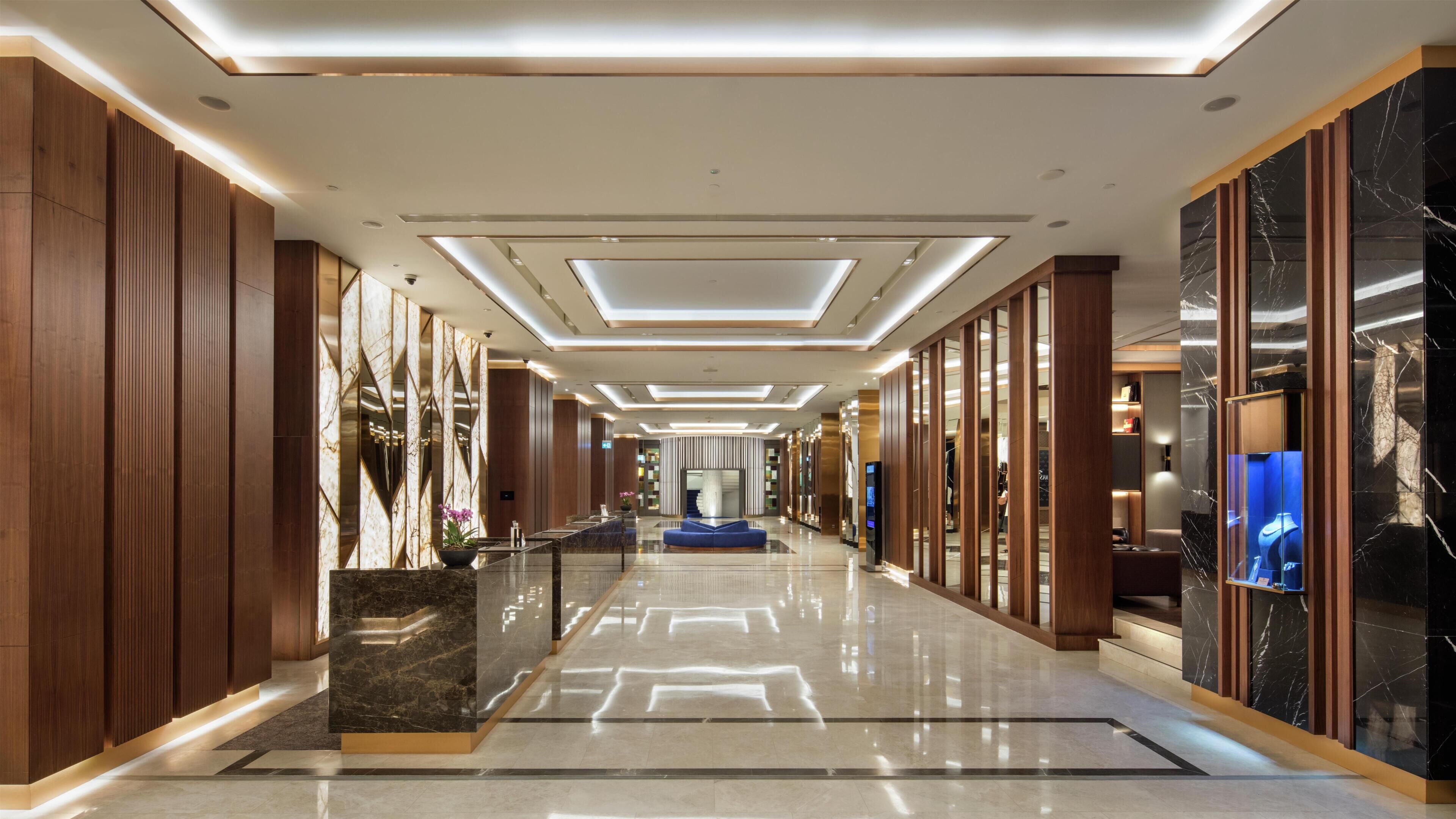 A modern hotel lobby with a marble reception desk, a central seating area, and a view of the interior.