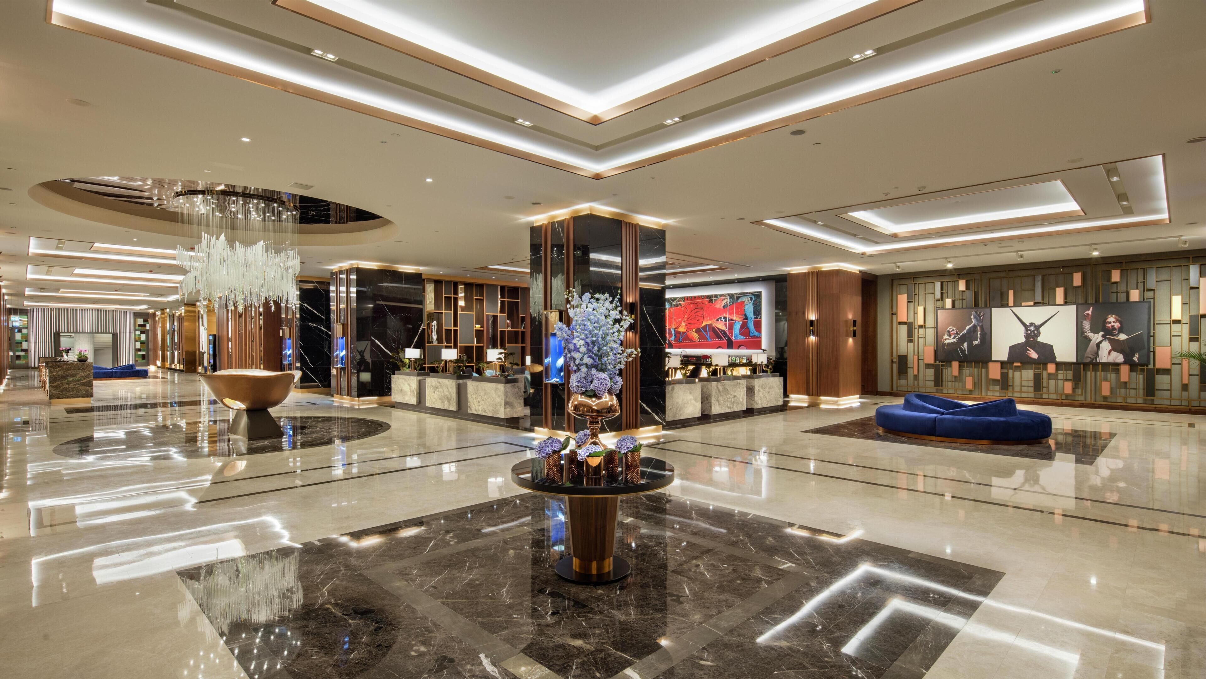A spacious lobby with a central fountain, a reception desk, and a seating area.