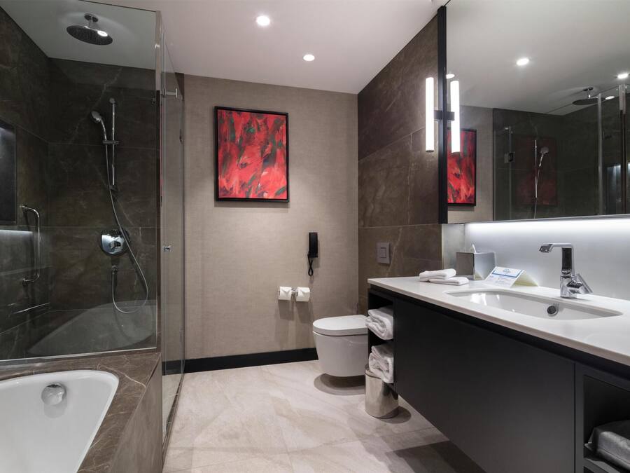 A modern bathroom with a glass-enclosed shower, a white bathtub, a large mirror, and a vanity with a sink.