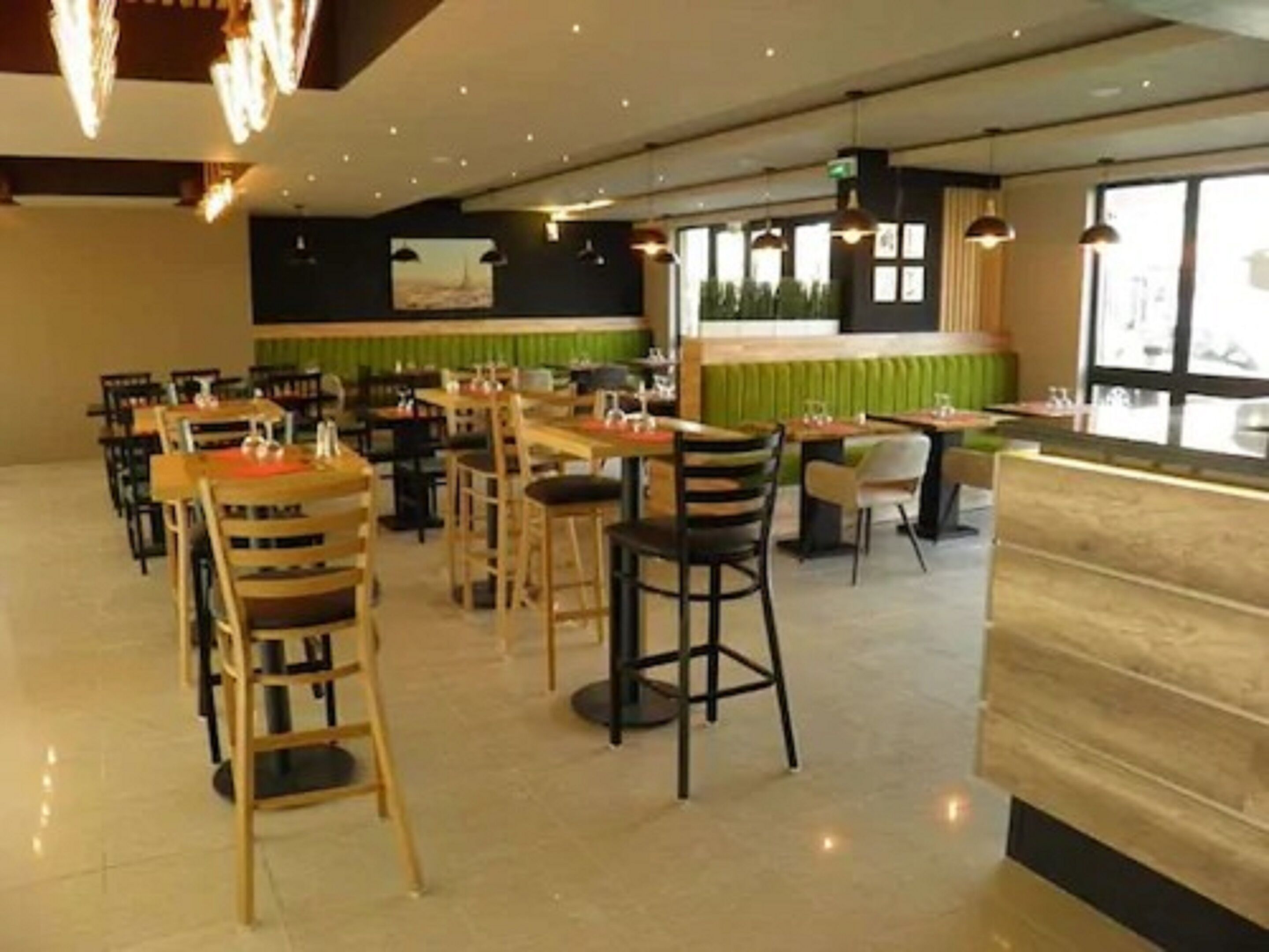 Un intérieur de restaurant moderne avec des tabourets de bar, des tables et des luminaires suspendus.