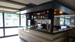 A modern bar area with a wooden counter, shelves with bottles, and a computer monitor. - Euro Hôtel Paris Créteil (Creteil)