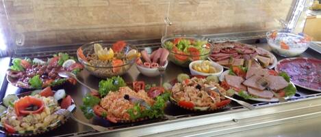 A buffet with various dishes including salads, meats, and other prepared foods.