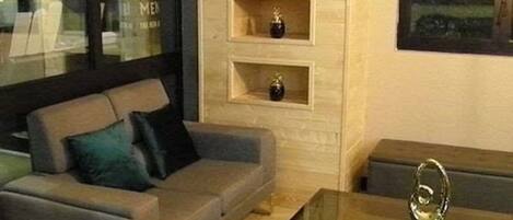 A modern living room with a grey sofa, a glass coffee table, and built-in shelving with decorative items.