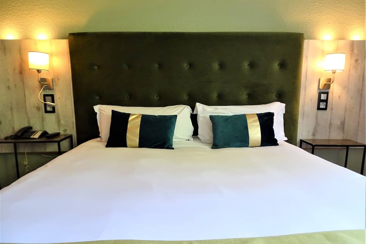 A neatly made bed with two pillows, a tufted headboard, and bedside lamps.