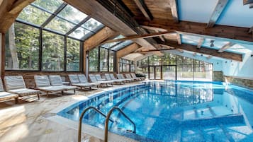 An indoor swimming pool with wooden beams and large windows.
