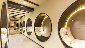 Un couloir d’hôtel aux murs recouverts de miroirs et doté d’espaces de détente circulaires.