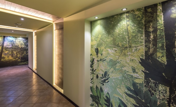 A corridor with a wall mural of a forest, a brick accent wall, and recessed lighting. - Lion Borovetz (Samokov)