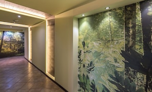 A corridor with a wall mural of a forest, a brick accent wall, and recessed lighting. - Lion Borovetz (Samokov)