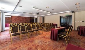 A conference room with rows of chairs, a table, and an exit sign. - Lion Borovetz (Samokov)