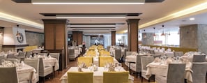 A restaurant with multiple tables, each with a white tablecloth and yellow chairs, and a modern interior design. - Lion Borovetz (Samokov)