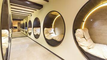 A corridor with multiple circular mirrors on the walls and a series of beds with headboards.