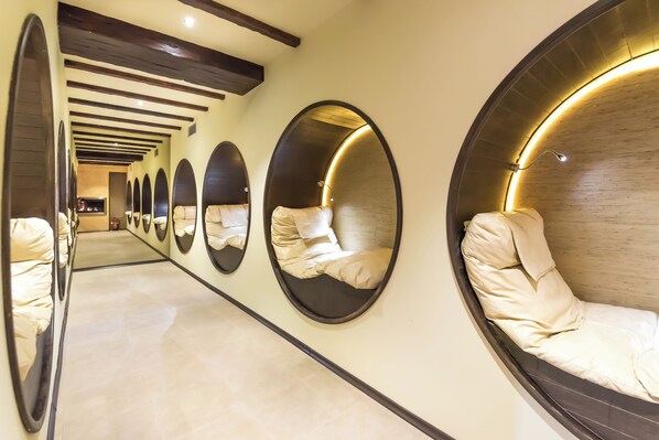 A corridor with multiple circular mirrors on the walls and a series of beds with headboards. - Lion Borovetz (Samokov)