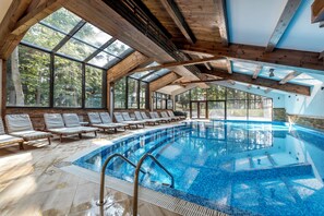 Una piscina interior con vigas de madera y ventanas grandes.