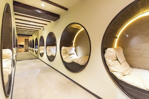 A corridor with multiple circular mirrors on the walls and a series of beds with headboards. - Lion Borovetz (Samokov)