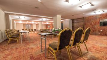 Un salón de conferencias con una larga mesa, sillas, piso alfombrado e iluminación en el techo.