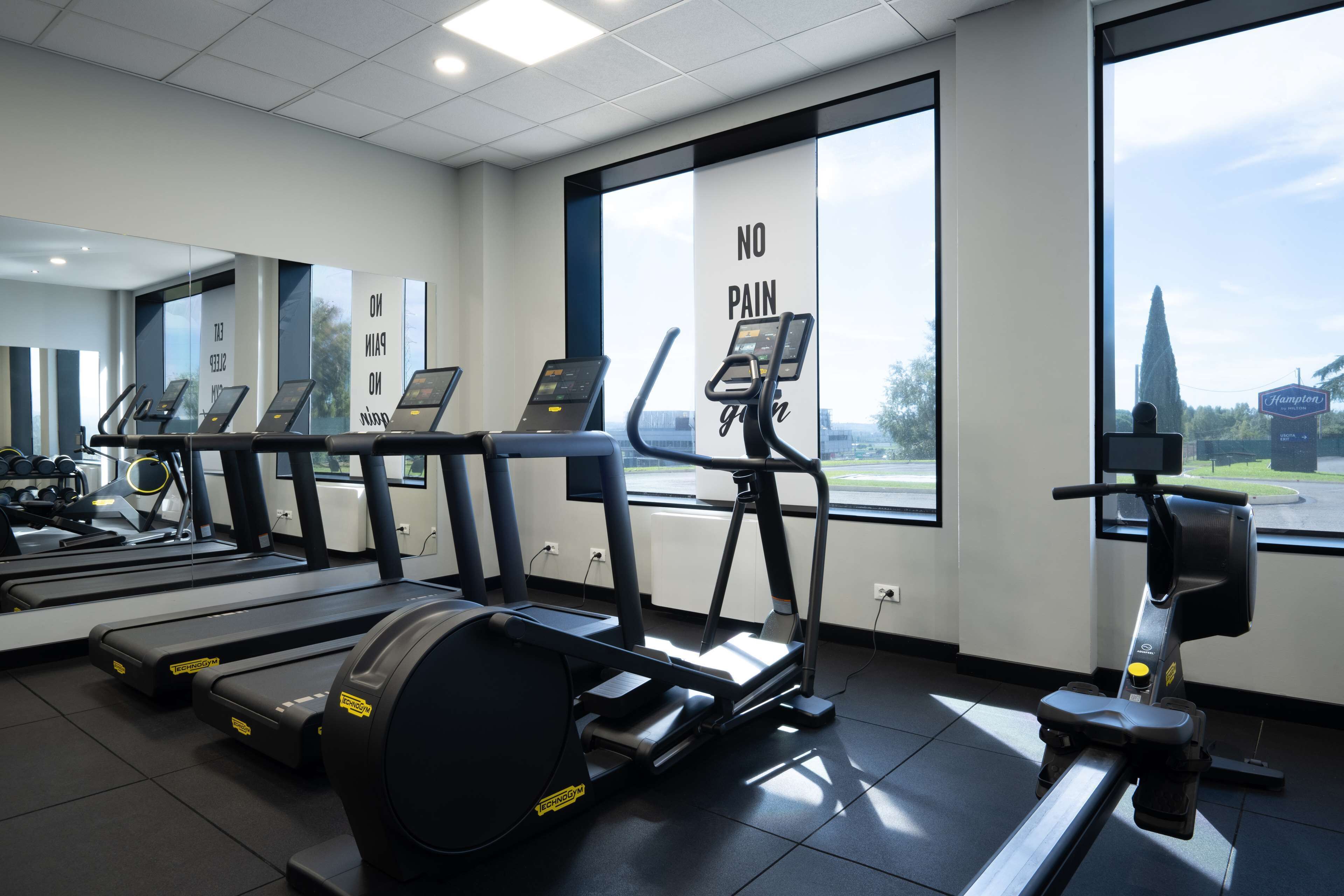 Un gimnasio con cintas de correr, una bicicleta estática y una máquina de remo.