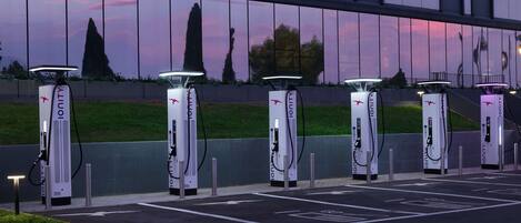 A row of electric vehicle charging stations with a modern building in the background.