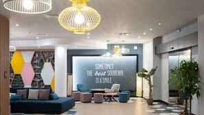 A modern lobby with a geometric wall design, a seating area with sofas and ottomans, and a motivational quote on the wall.
