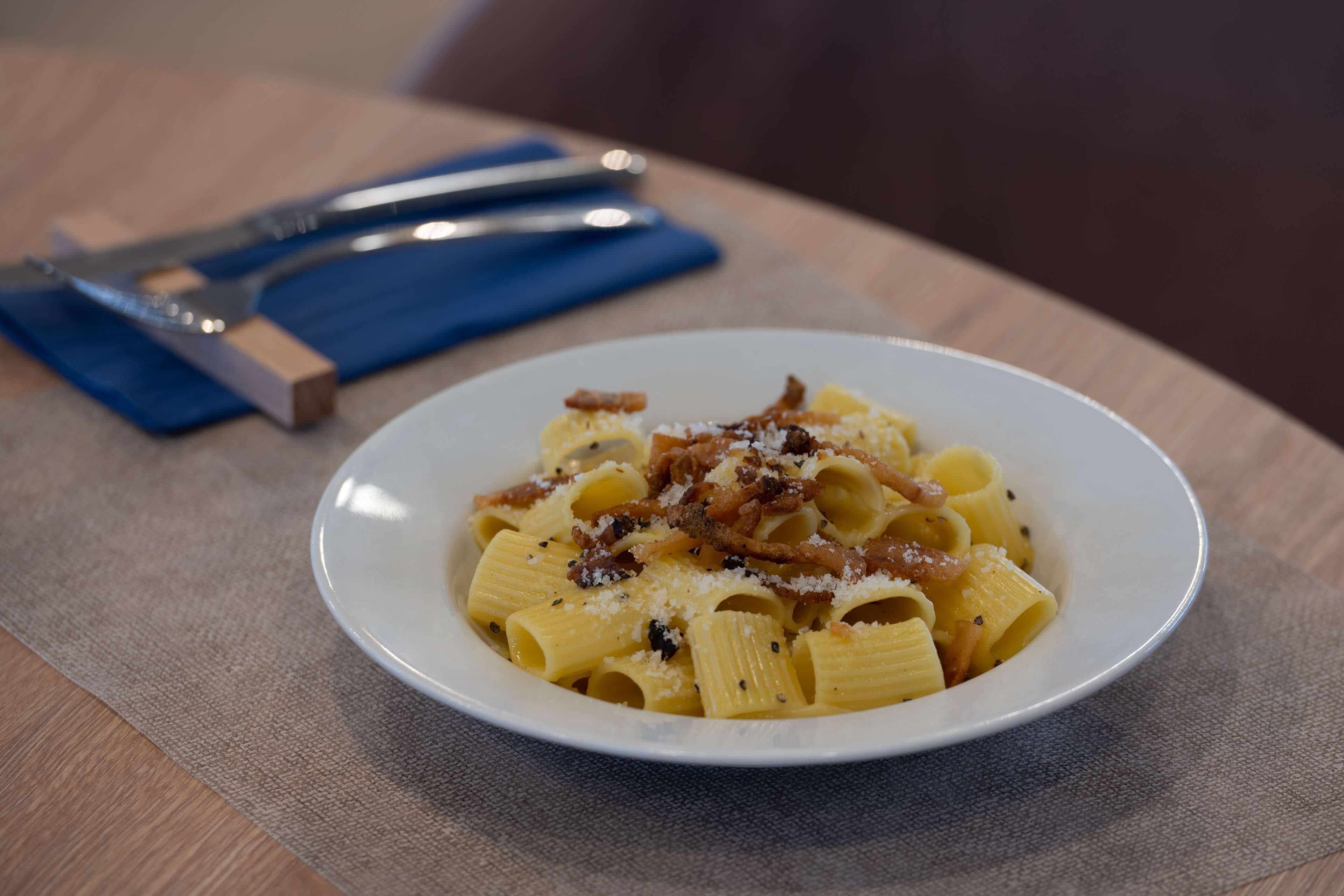 Un plato de pasta con queso y tocino sobre una mesa.