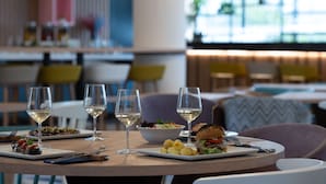 A dining table with plates of food, glasses of white wine, and cutlery.