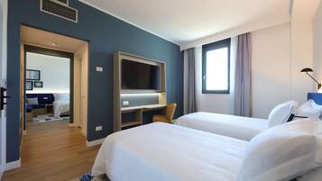 A hotel room with two beds, a TV, and a desk.
