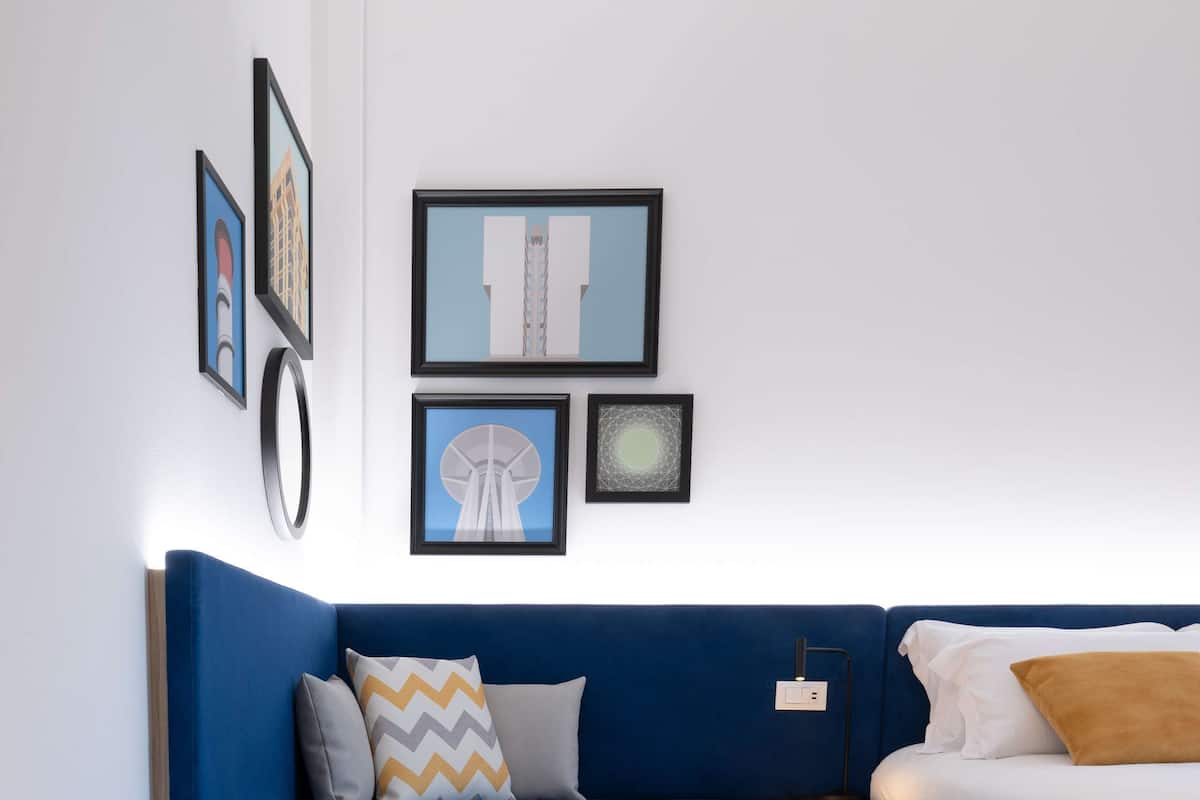 A modern bedroom with a blue sofa, a bed, a bedside table, and a rug.