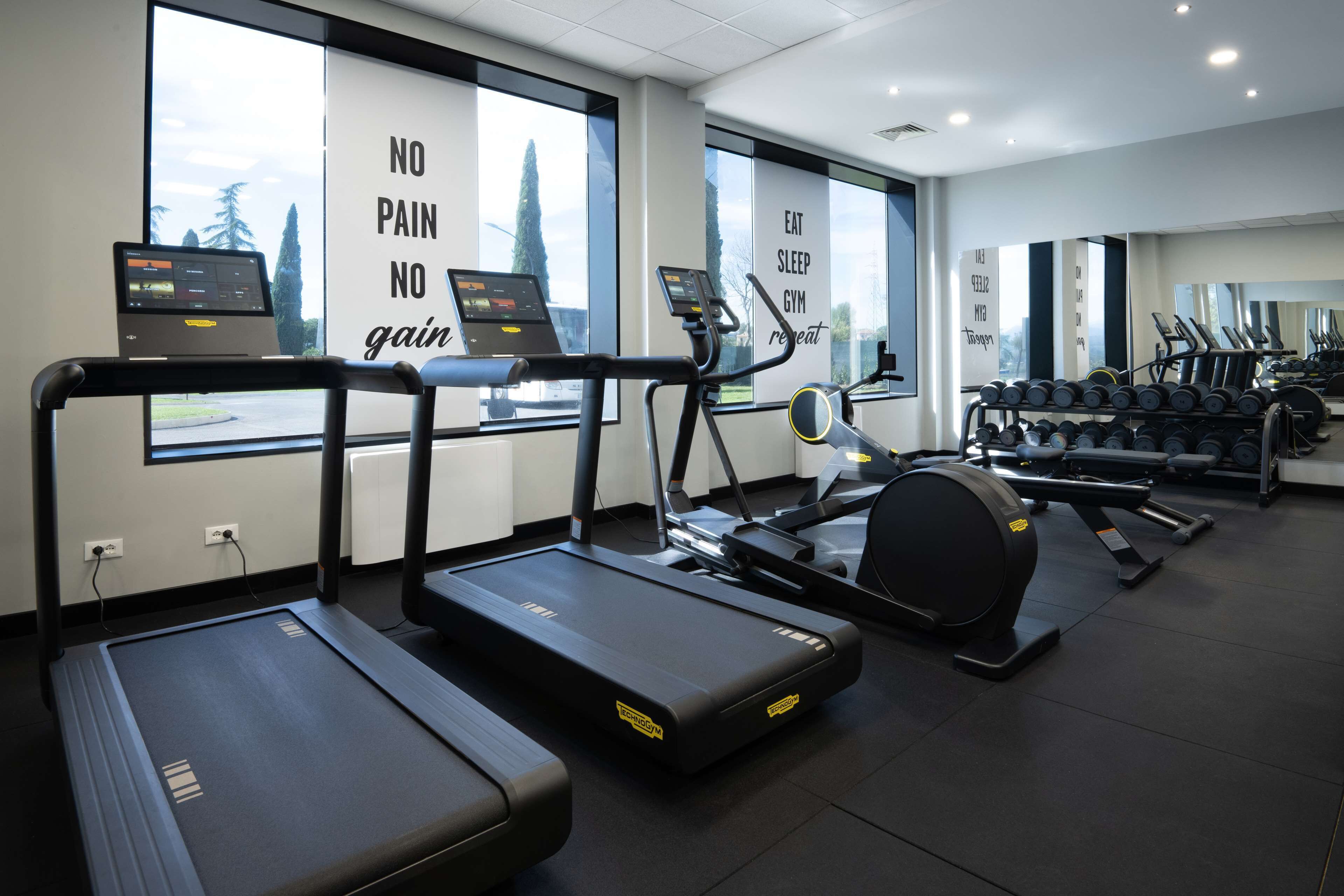 A gym with treadmills, a rowing machine, and dumbbells.