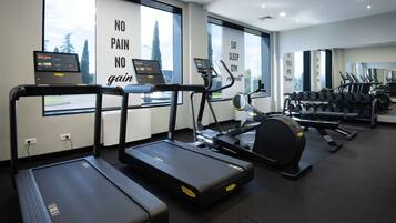 A gym with treadmills, a rowing machine, and dumbbells.