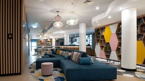 A modern lobby with a sectional sofa, a patterned rug, and a geometric bookshelf.