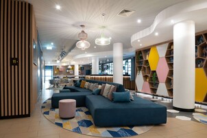 Un vestíbulo moderno con un sofá modular, un tapete estampado y una estantería geométrica.