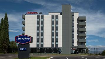 Un hotel Hampton by Hilton con un diseño moderno, que presenta una entrada destacada y un estacionamiento.