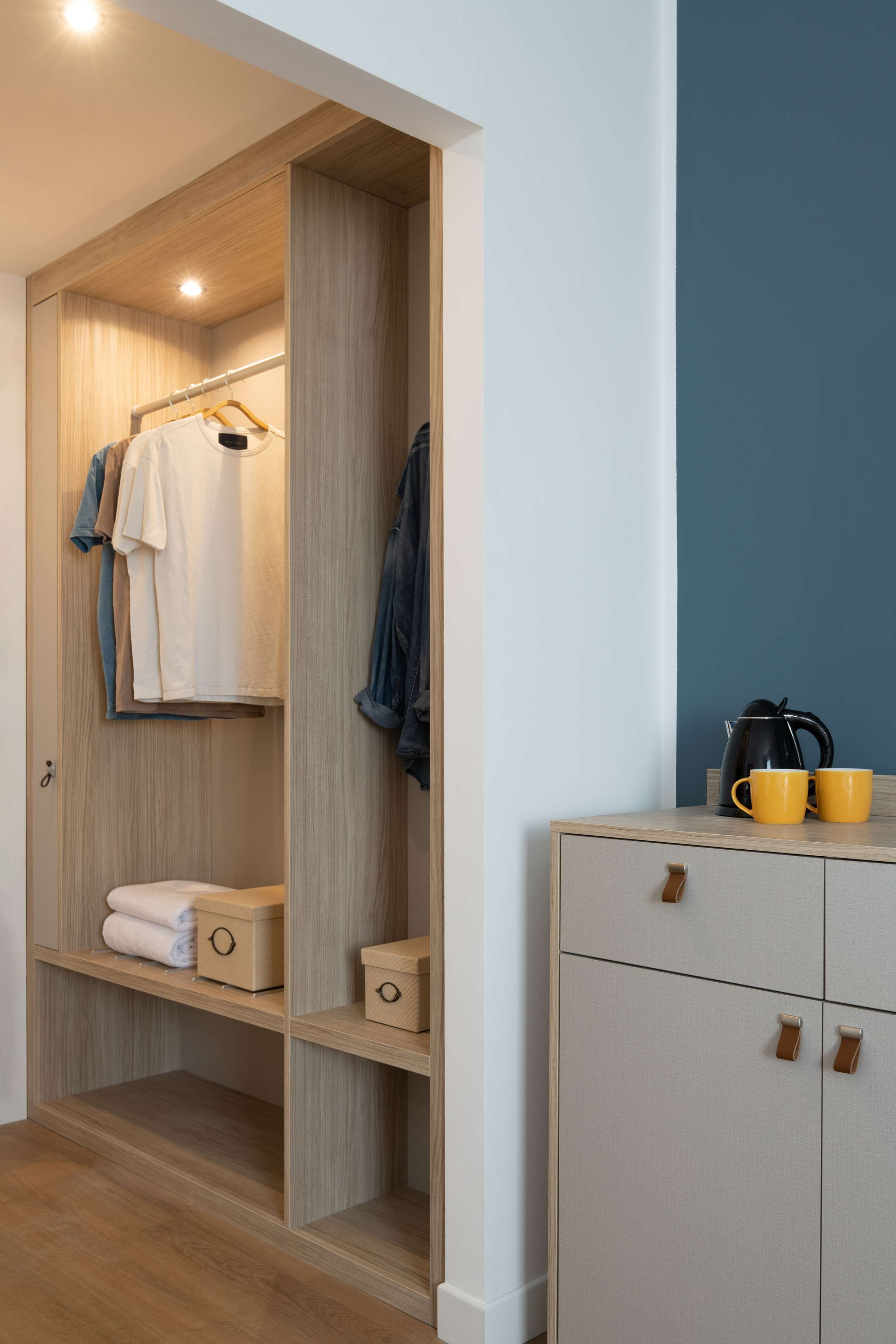 Um closet espaçoso com prateleiras de madeira, roupas penduradas e caixas de armazenamento.