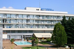 Un hotel de varios pisos con un letrero de Coca-Cola, piscina y zonas de estar al aire libre.