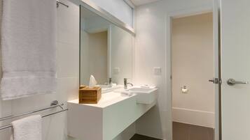 A modern bathroom with a white vanity, two sinks, a large mirror, and a towel rack.