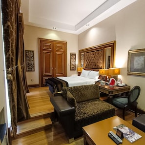 A hotel room with a bed, two bedside tables, a desk with a chair, a sofa, and a large mirror. - Sultan Inn Boutique (Baku)
