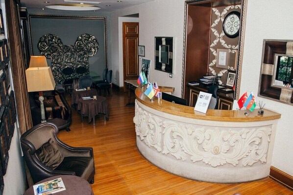 A reception area with a curved reception desk, several flags, a clock, and a mirror on the wall.