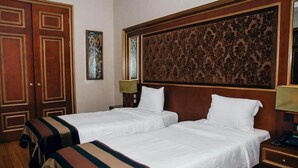 A hotel room with two beds, wooden wardrobe, and a decorative headboard. - Sultan Inn Boutique (Baku)