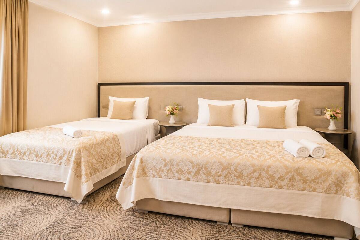 A hotel room with two beds, a headboard, bedside tables, and a carpeted floor.