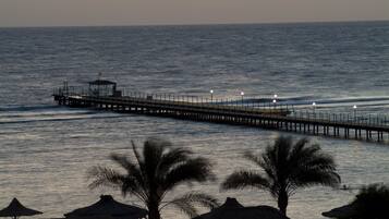 A pier extending into calm waters with a thatched-roof structure at the end.