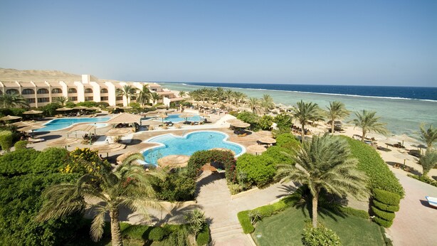 Et resort med flere swimmingpools, palmer og havudsigt.