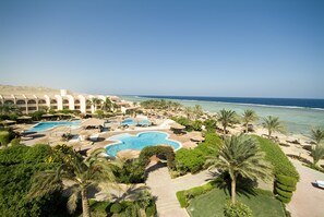 Un resort con múltiples piscinas, palmeras y vistas a la playa.