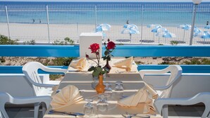 Une table à manger dressée pour deux personnes, avec vue sur la plage et l’océan.