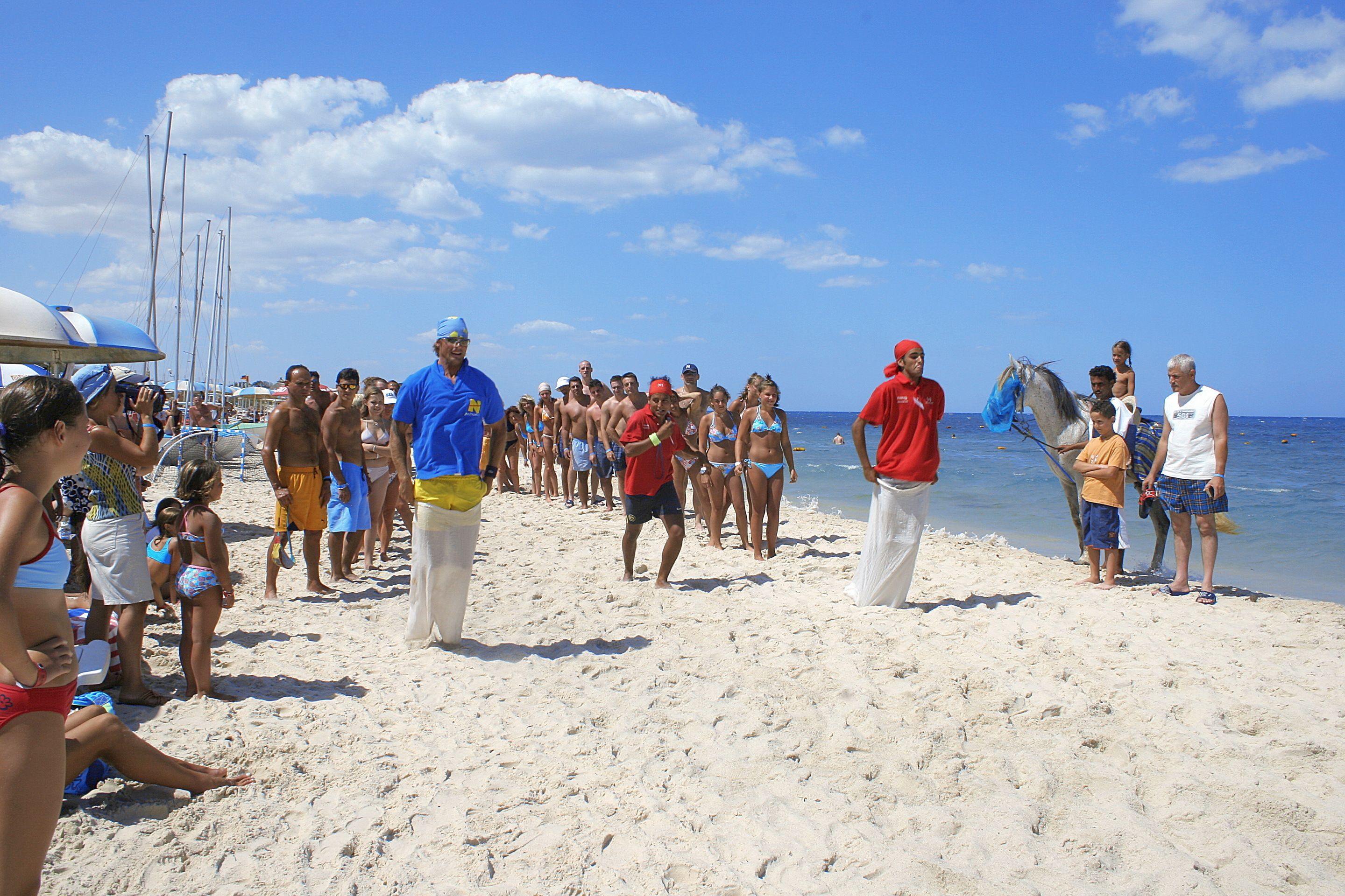 A beach scene with people, boats, and a clear sky.