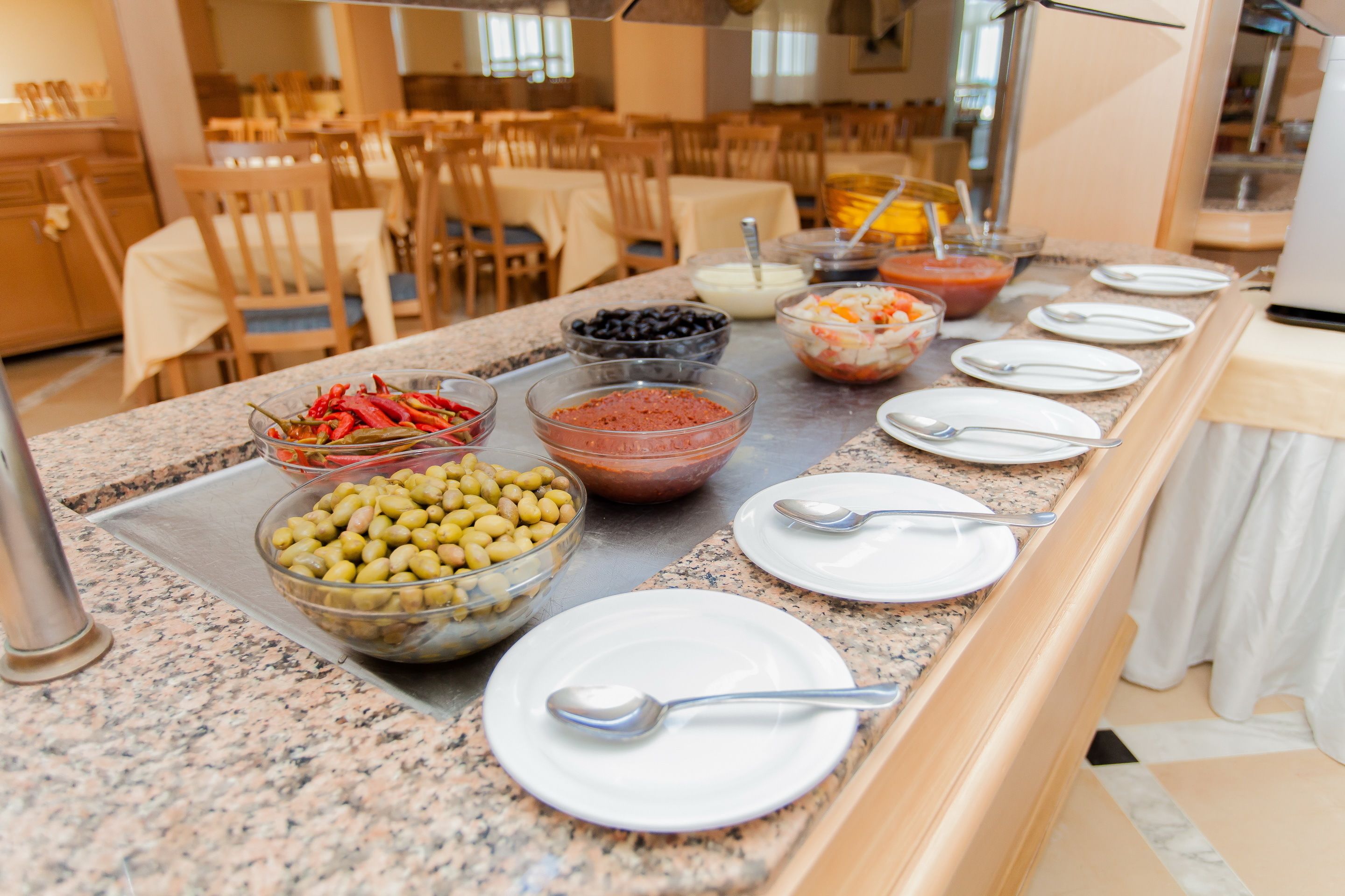 Una mesa de buffet con distintos alimentos y utensilios.