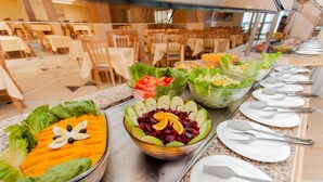 Un buffet proposant une variété de salades et de fruits, disposés sur un comptoir avec des assiettes et des couverts.